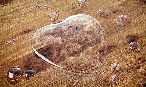 Massiv-Holzmöbel ölen: Wasser in Form eines Herzens perlt von der Oberfläche ab.